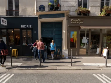 Des personnes entrent dans le Passage de l'Ancre situé entre deux commerces parisiens.