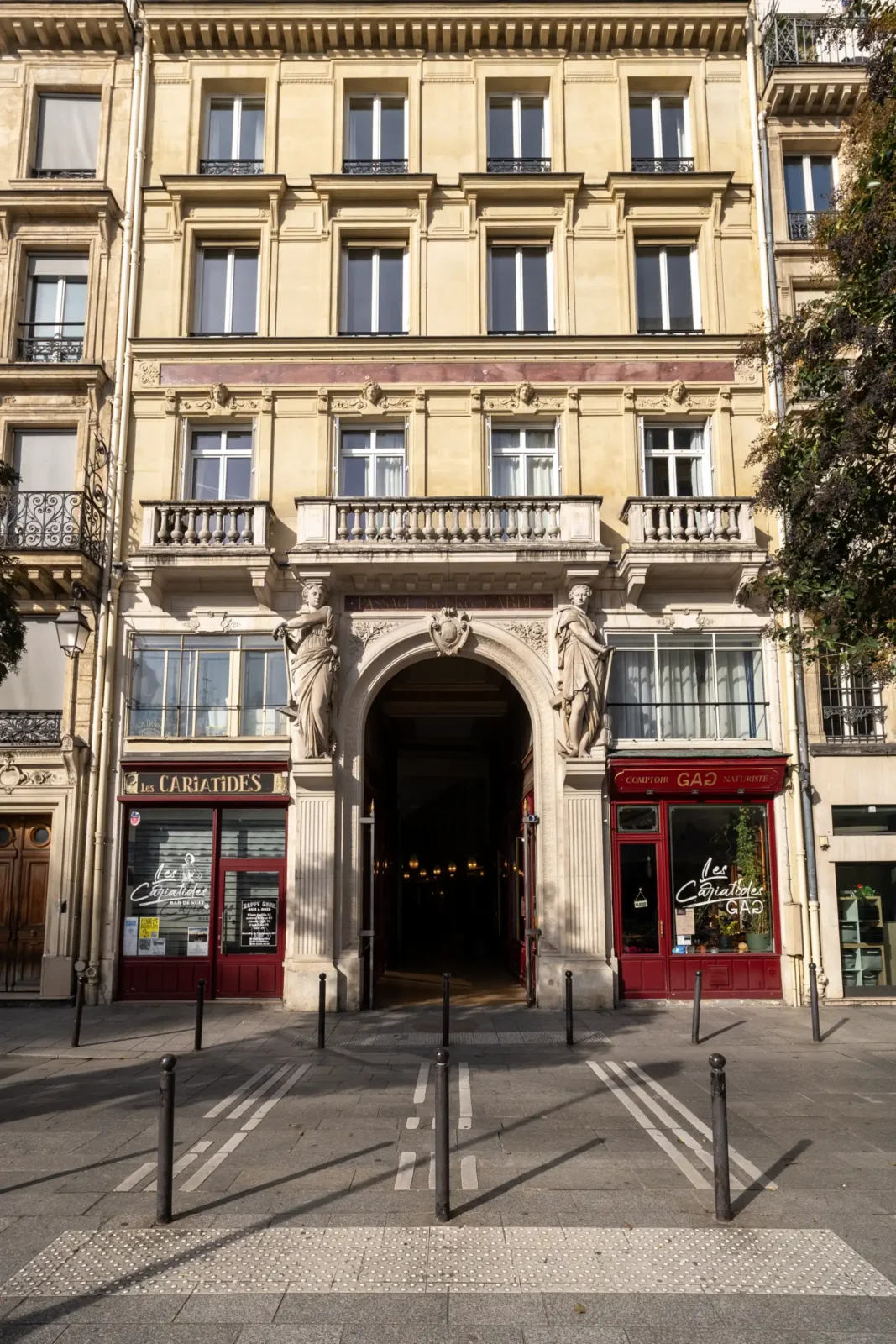 Façade classique du Passage du Bourg-l'Abbé à Paris ornée de deux imposantes statues sculptées.