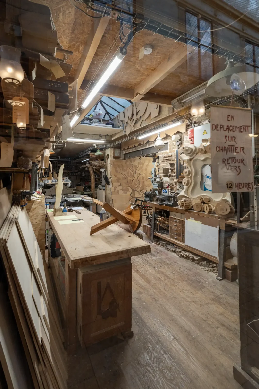 Vue intérieure d'un atelier de menuiserie encombré situé dans le passage Bourg l'Abbé.