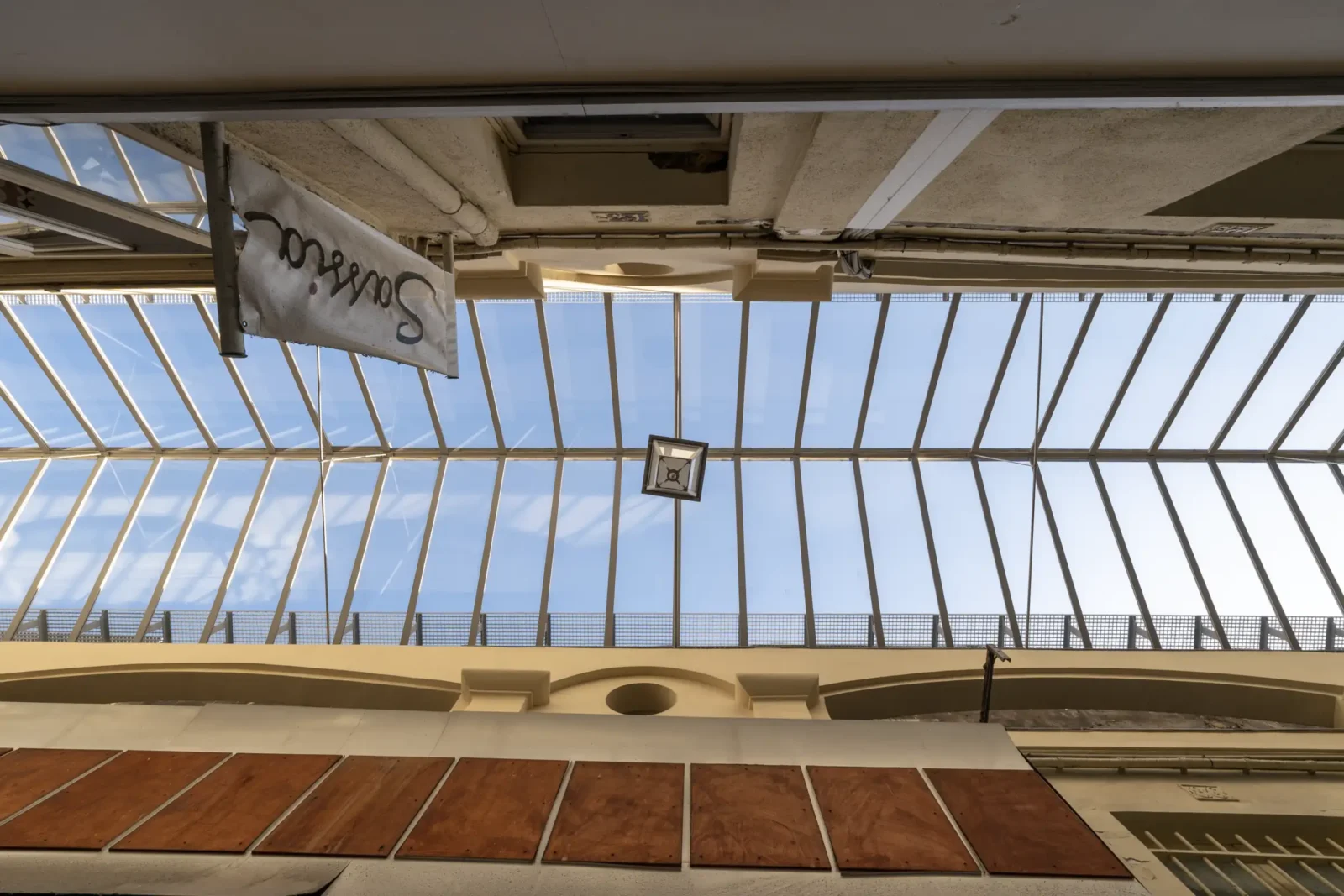 Vue en contre-plongée de la verrière du passage du Caire avec une enseigne suspendue.