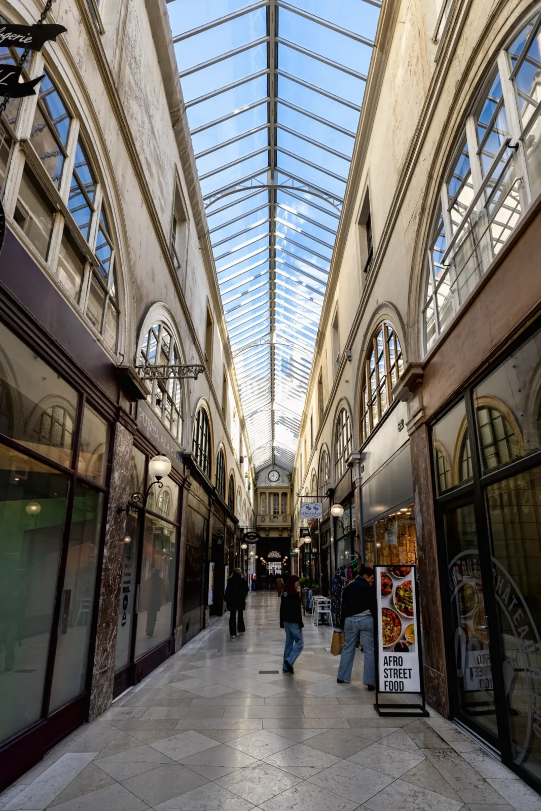 Une vue en perspective du Passage Choiseul à Paris sous une verrière lumineuse.