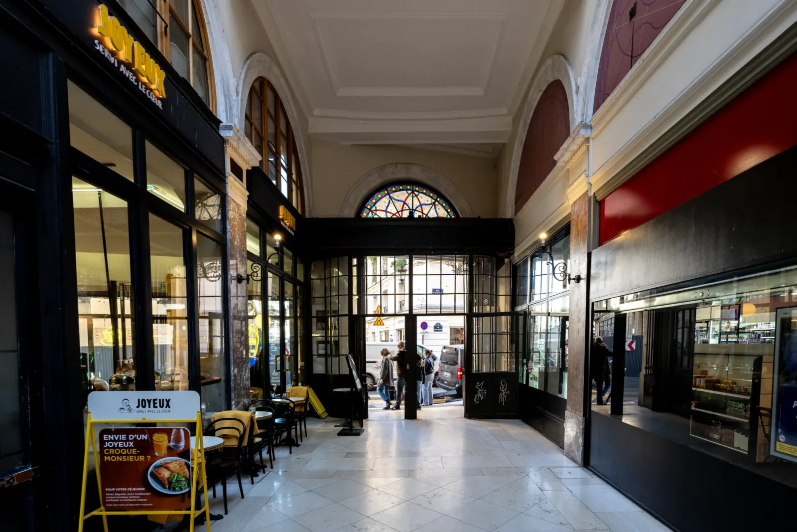 Vue intérieure du Passage Choiseul à Paris avec ses boutiques et son vitrail coloré.