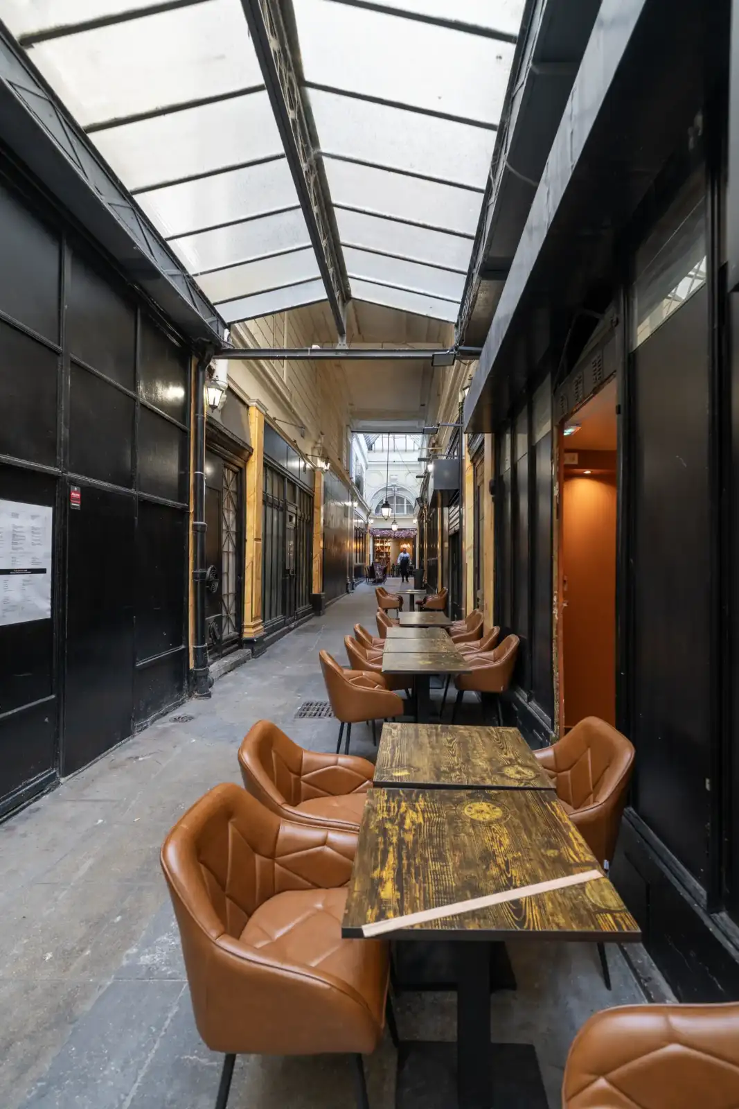 Vue intérieure du Passage Feydeau à Paris avec des tables de café et un toit vitré.