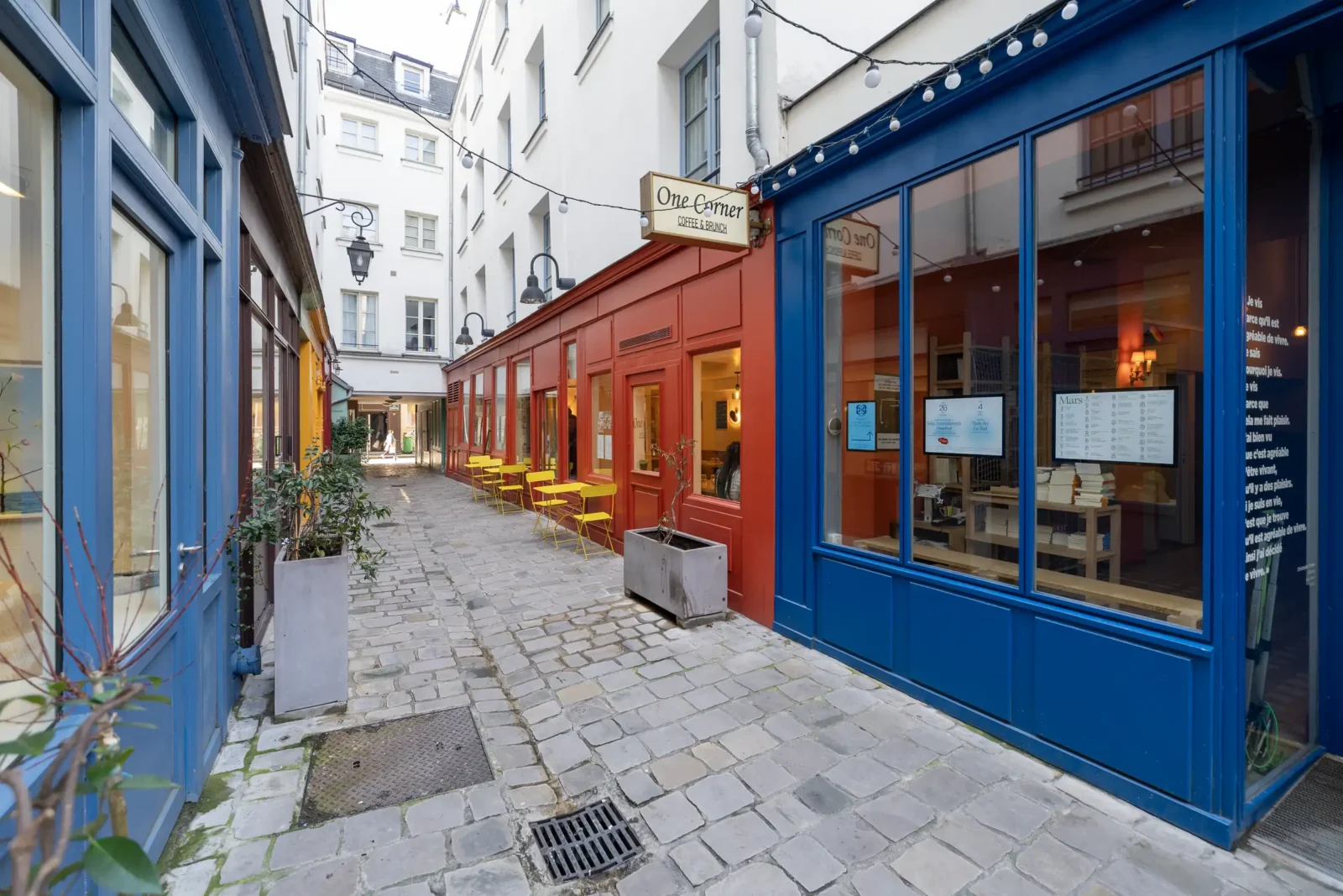 Une ruelle pavée étroite bordée de façades colorées et de terrasses dans Paris.
