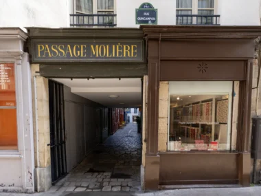 L'entrée pavée du Passage Molière à Paris avec une boutique de papier artisanal adjacente.