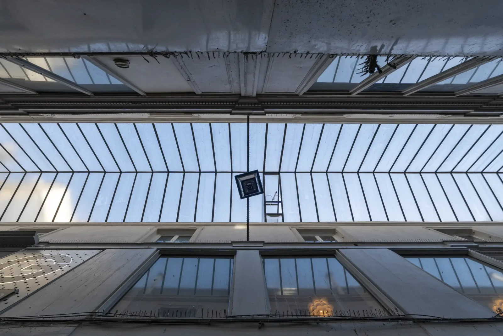 Vue en contre-plongée de la verrière et des façades du Passage Ponceau à Paris.
