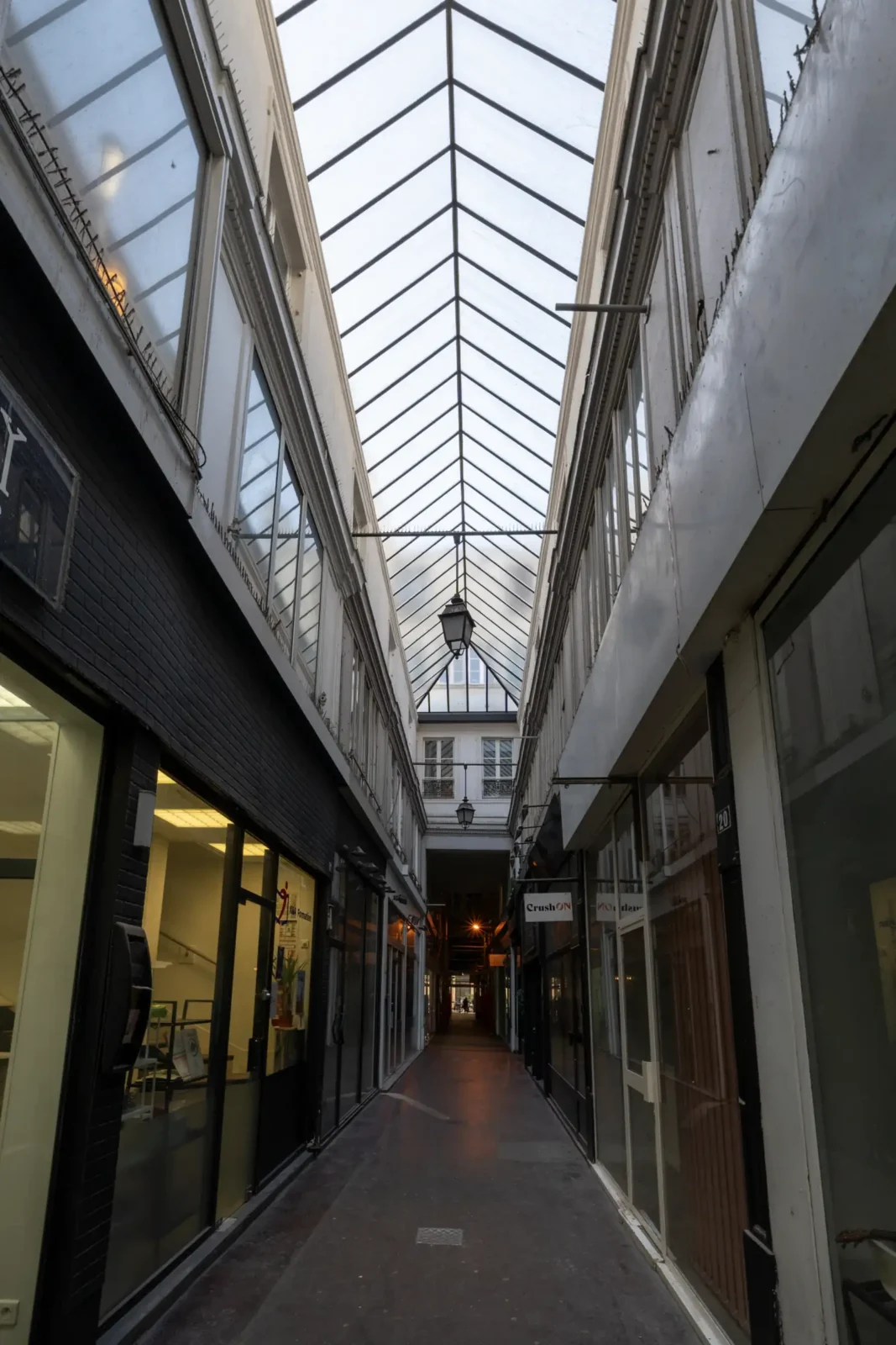 Vue intérieure du Passage du Ponceau à Paris sous une verrière lumineuse et étroite.