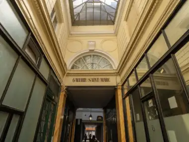Vue en contre-plongée de la verrière et de la façade de la galerie Saint-Marc à Paris.