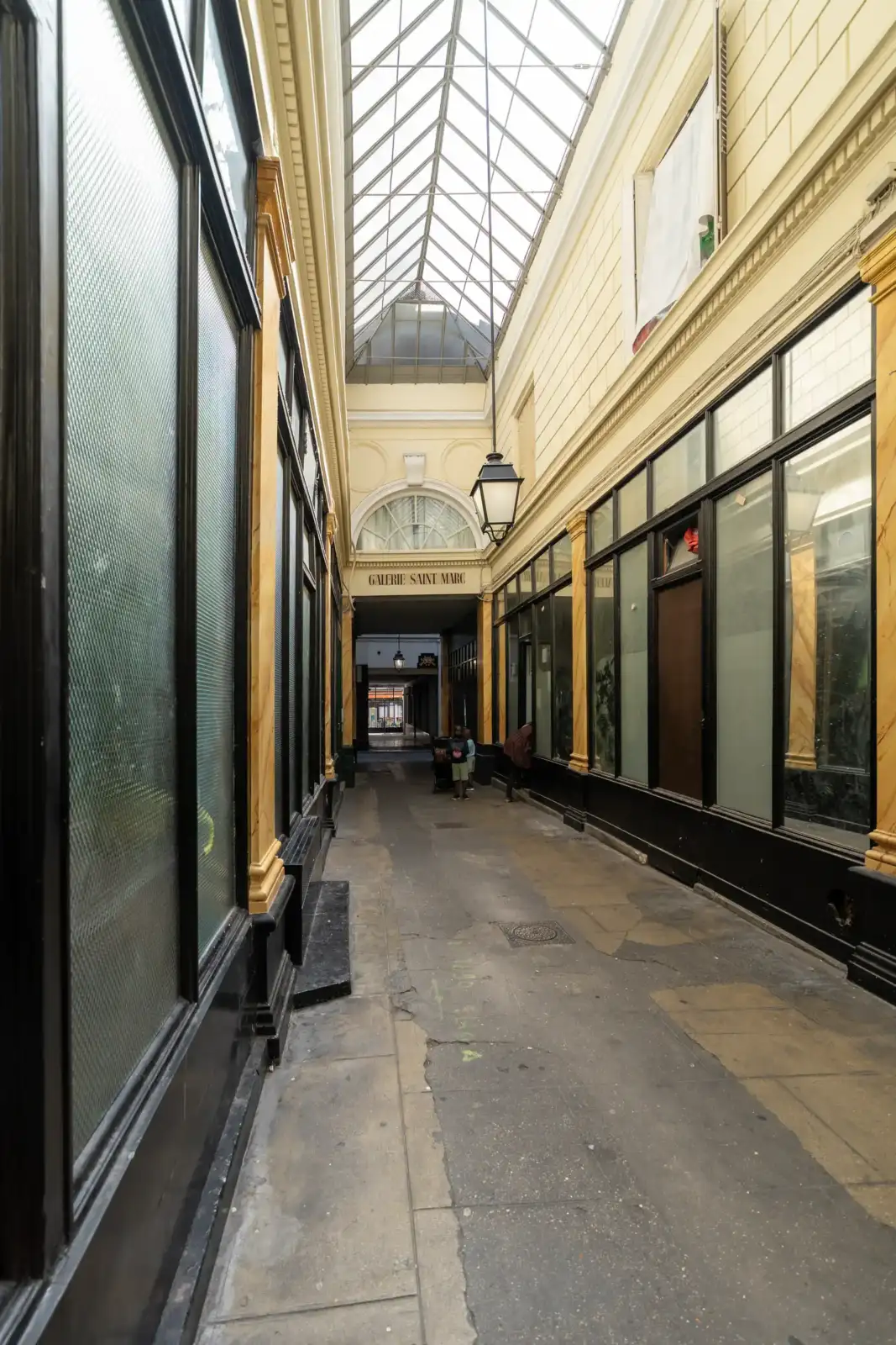 Vue intérieure du passage Saint-Marc à Paris, avec une verrière et des vitrines anciennes.