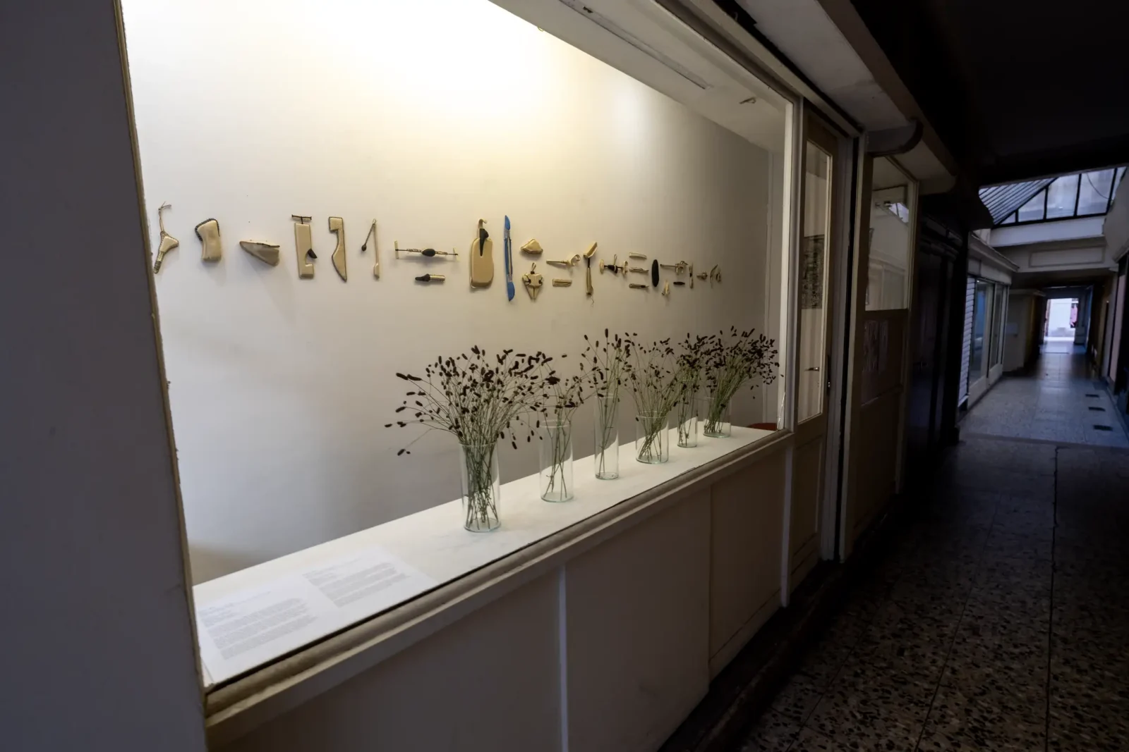 Une vitrine du Passage Sainte-Anne présente des objets muraux et des fleurs séchées.