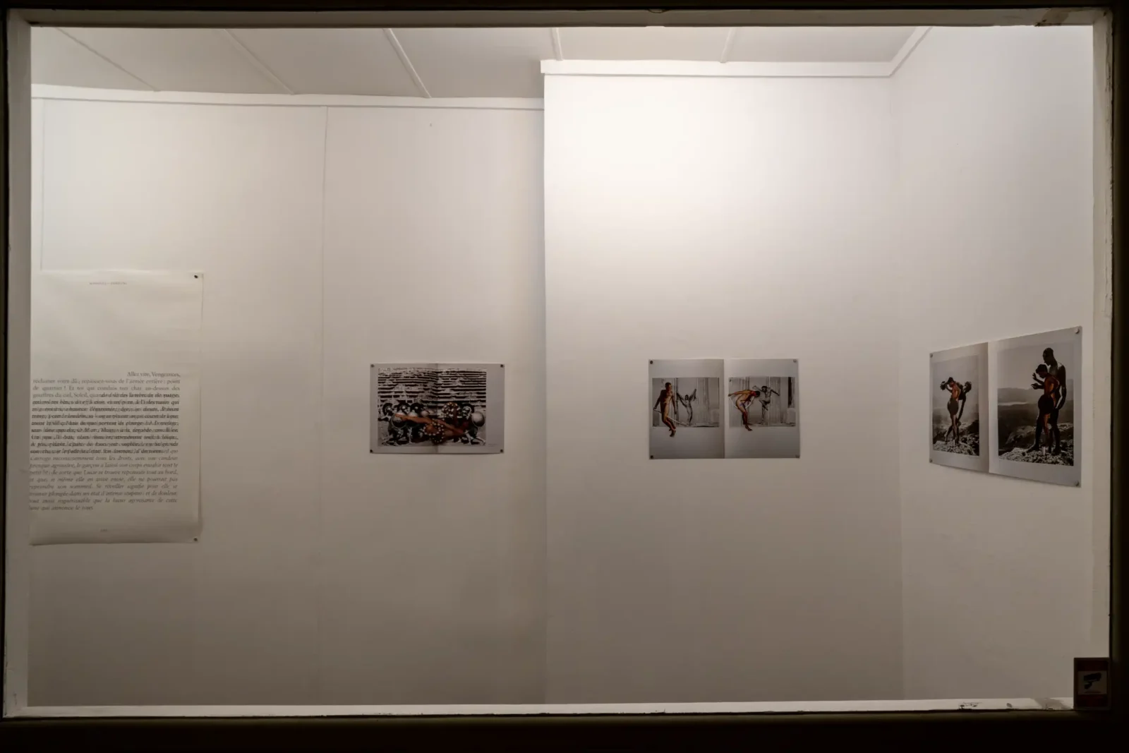 Des photographies et un texte sont exposés sur les murs blancs d'une galerie parisienne.