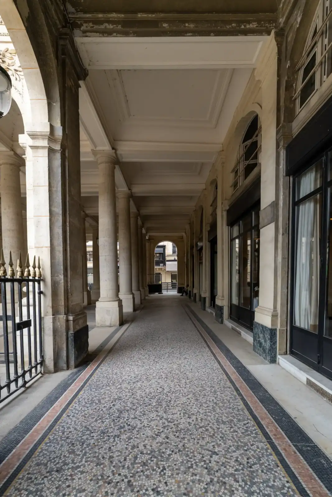 Vue intérieure d'une galerie couverte à colonnades et sol en mosaïque à Paris.