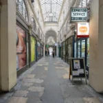 Le Passage Vendôme à Paris présente une allée couverte bordée de boutiques et publicités.