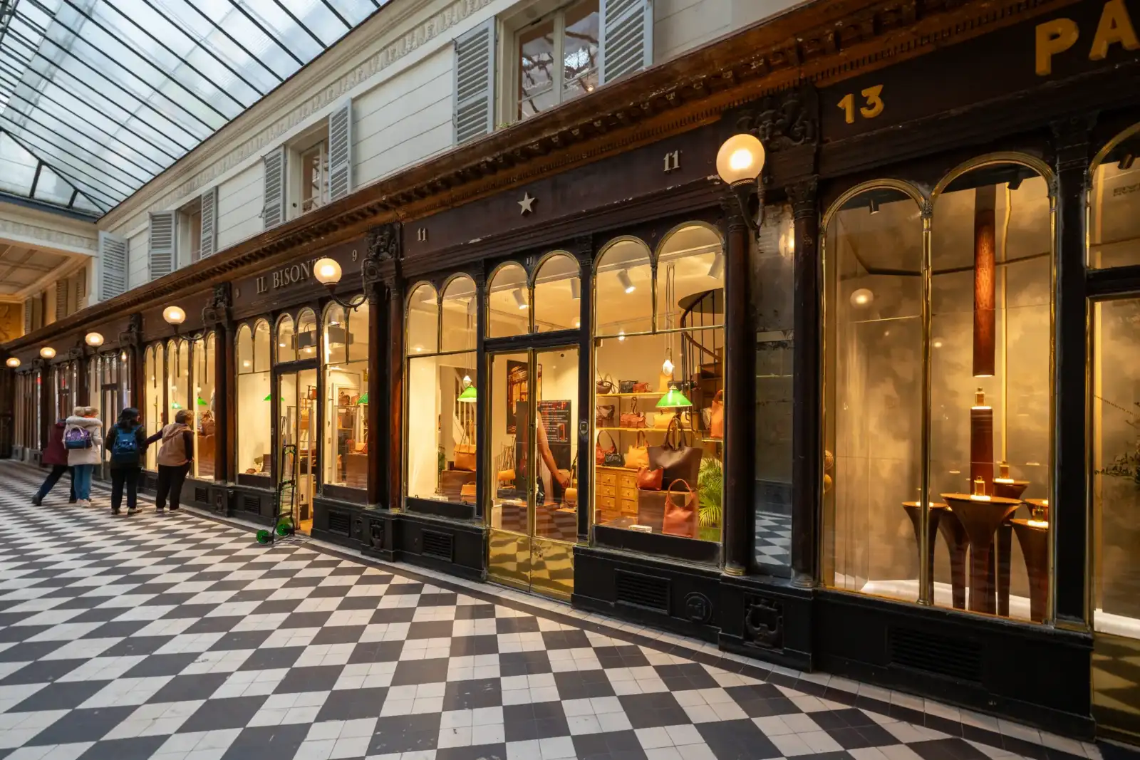 Les passants marchent dans le Passage Véro-Dodat sous une verrière au sol en damier.