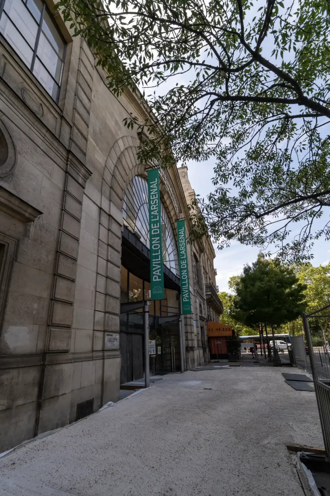 Une vue en contre-plongée du Pavillon de l'Arsenal avec des bannières vertes accrochées.