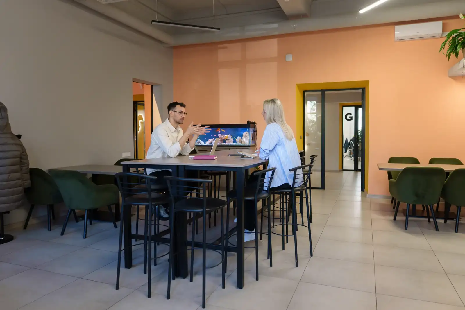Deux collègues discutent en face à face dans un espace de coworking coloré.