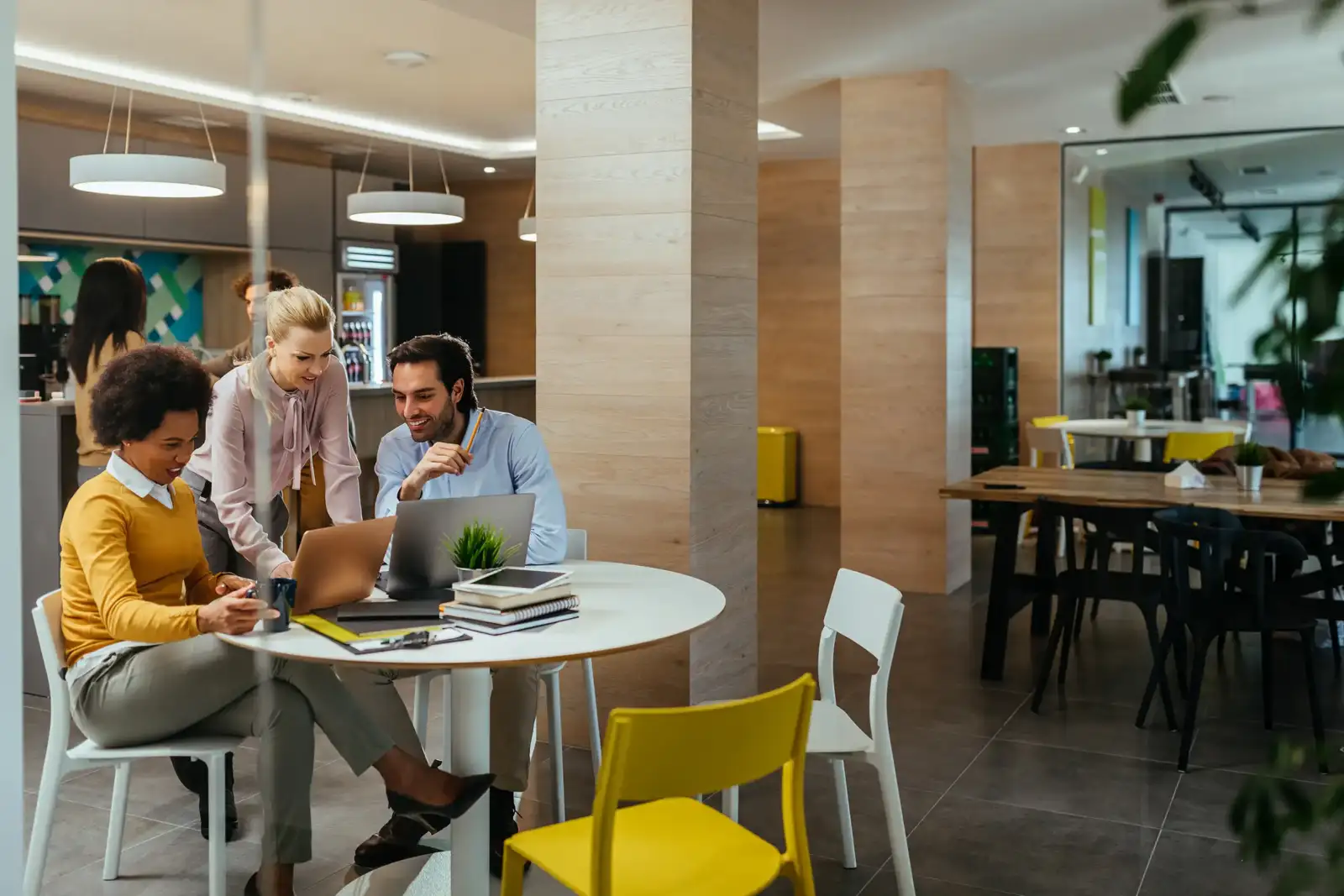 Trois professionnels travaillent ensemble autour d une table dans un espace de coworking lumineux.