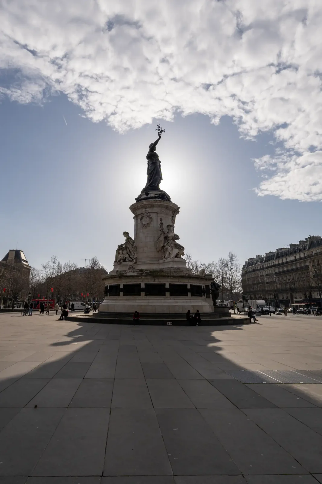 La statue monumentale de la République se dresse sous un ciel ensoleillé à Paris.