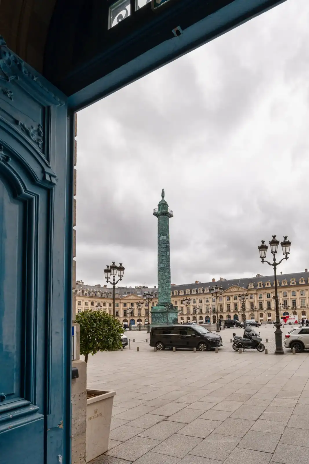 Vue encadrée de la place Vendôme à Paris avec sa colonne sous un ciel nuageux.
