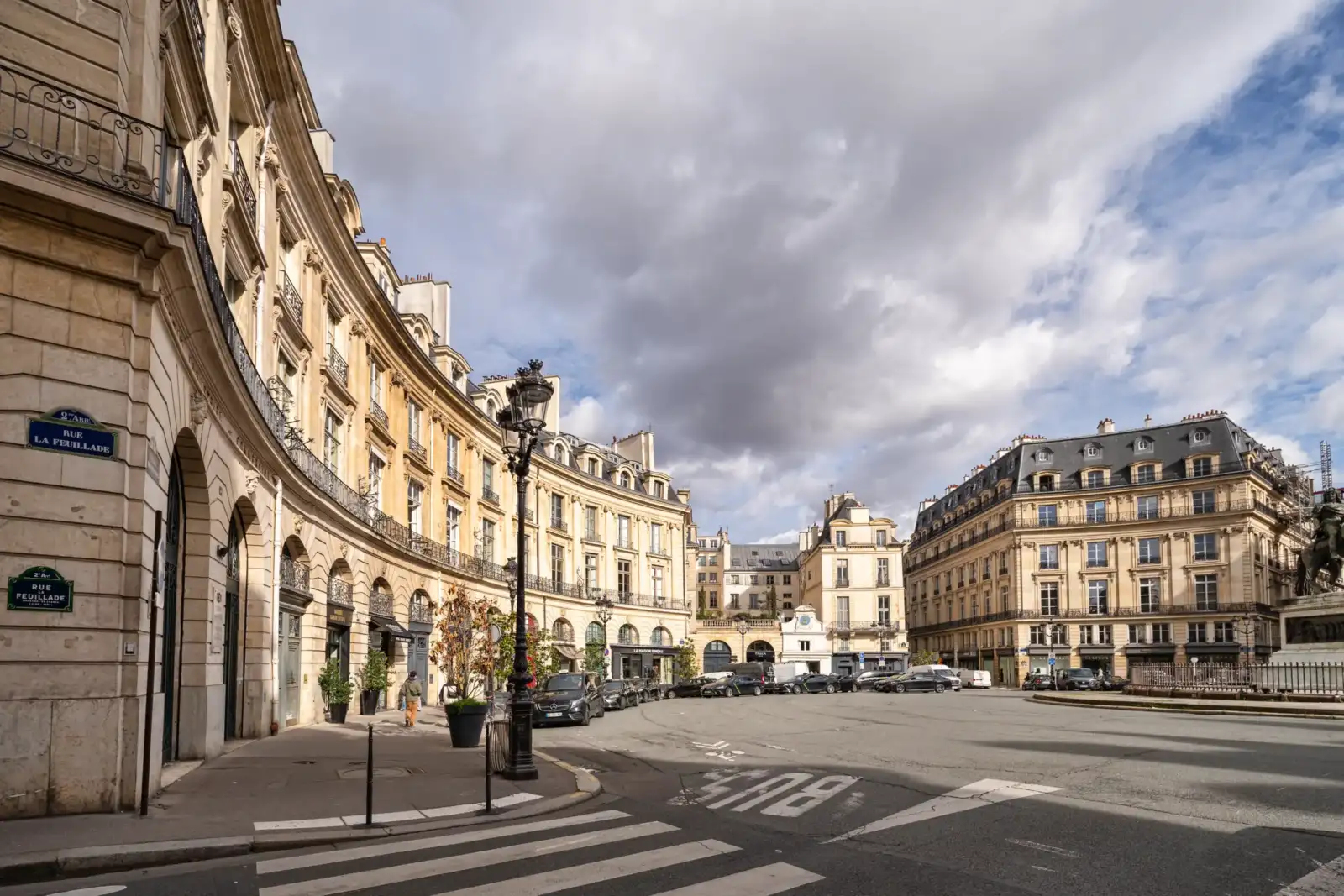 Vue en angle de la place des Victoires à Paris sous un ciel nuageux.