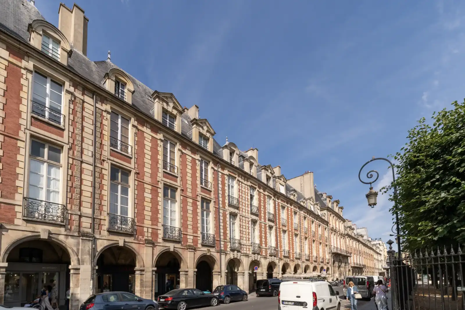 Façade historique en briques rouges et arcades de la place des Vosges à Paris.