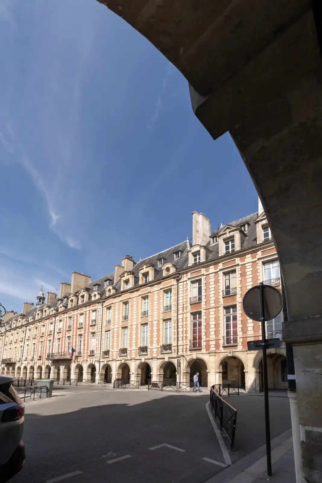 Une vue encadrée par une arche montre la magnifique façade classique parisienne sous le ciel.