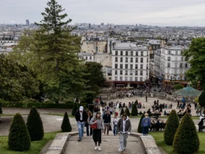 Des gens descendent les escaliers du parc de Montmartre avec Paris en arrière-plan.