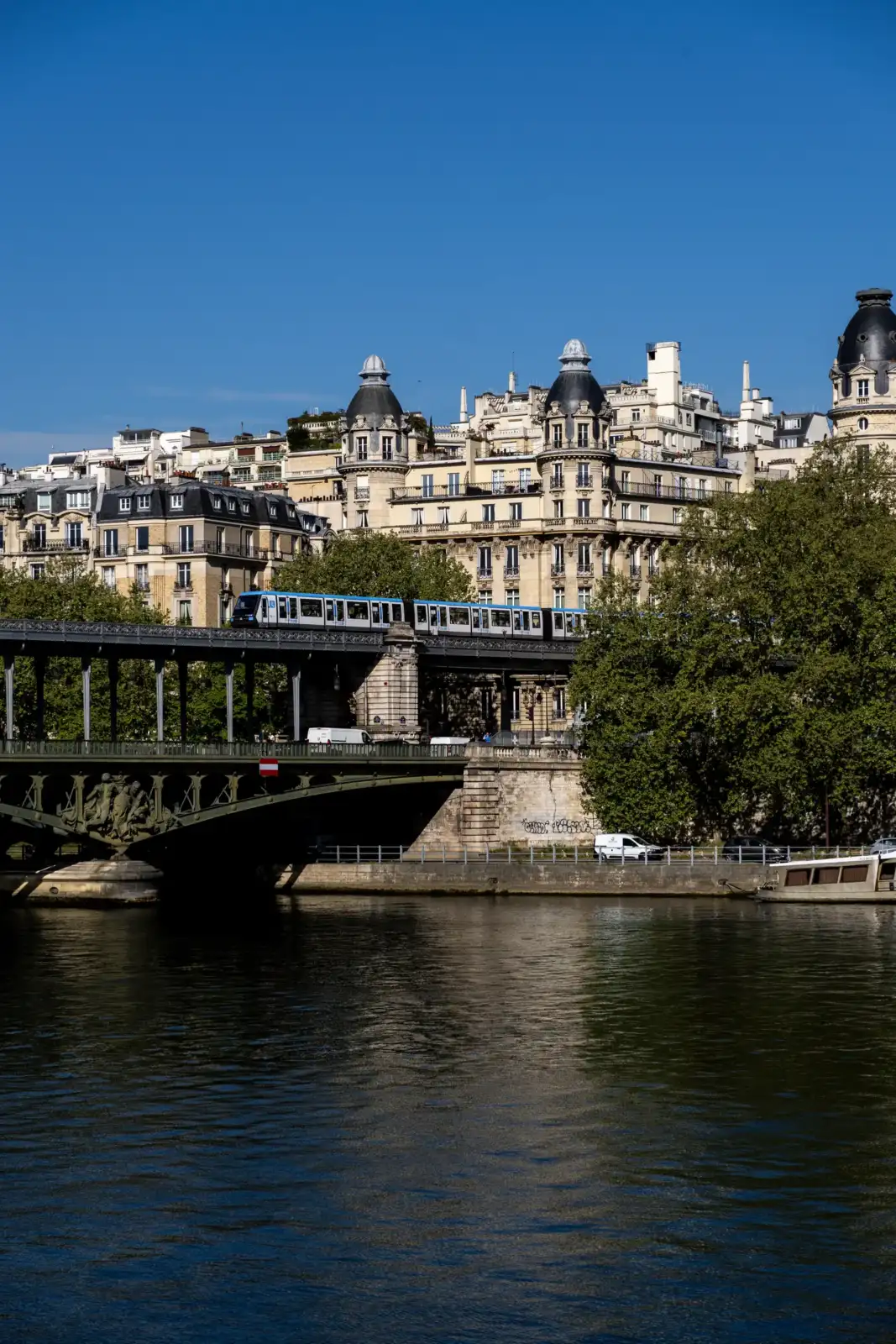 Un métro traverse le pont de Bir-Hakeim à Paris sous un ciel bleu éclatant.