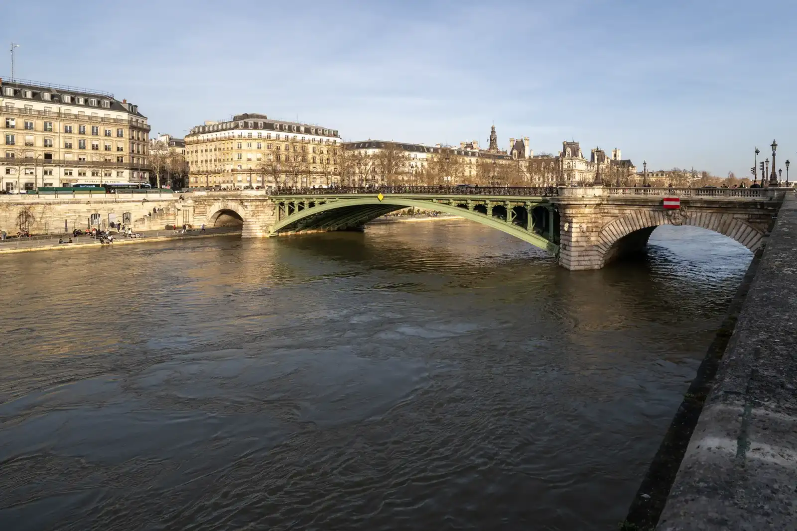 Un pont en métal vert traverse la Seine devant les façades classiques de Paris.