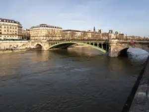Un pont en métal vert traverse la Seine devant les façades classiques de Paris.