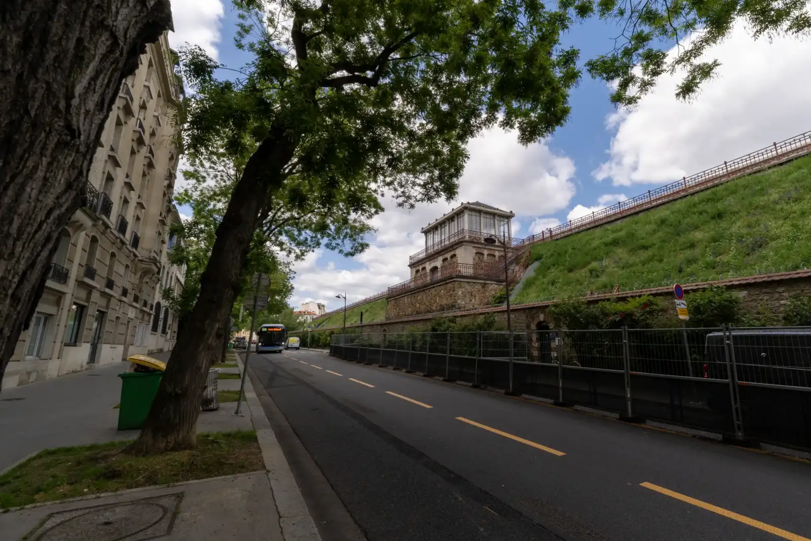 Vue extérieure du réservoir de Montsouris à Paris, bordé par une rue et de la verdure.