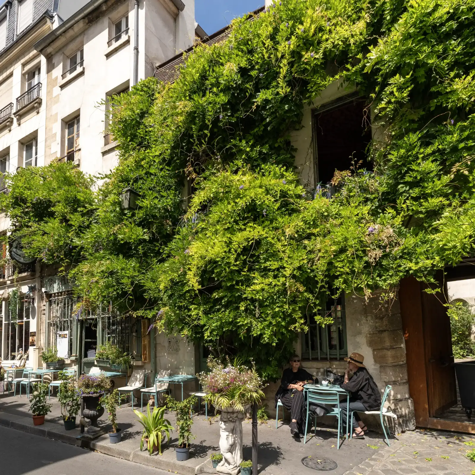 Vue de la façade du restaurant Au Vieux Paris d'Arcole recouverte de végétation luxuriante.