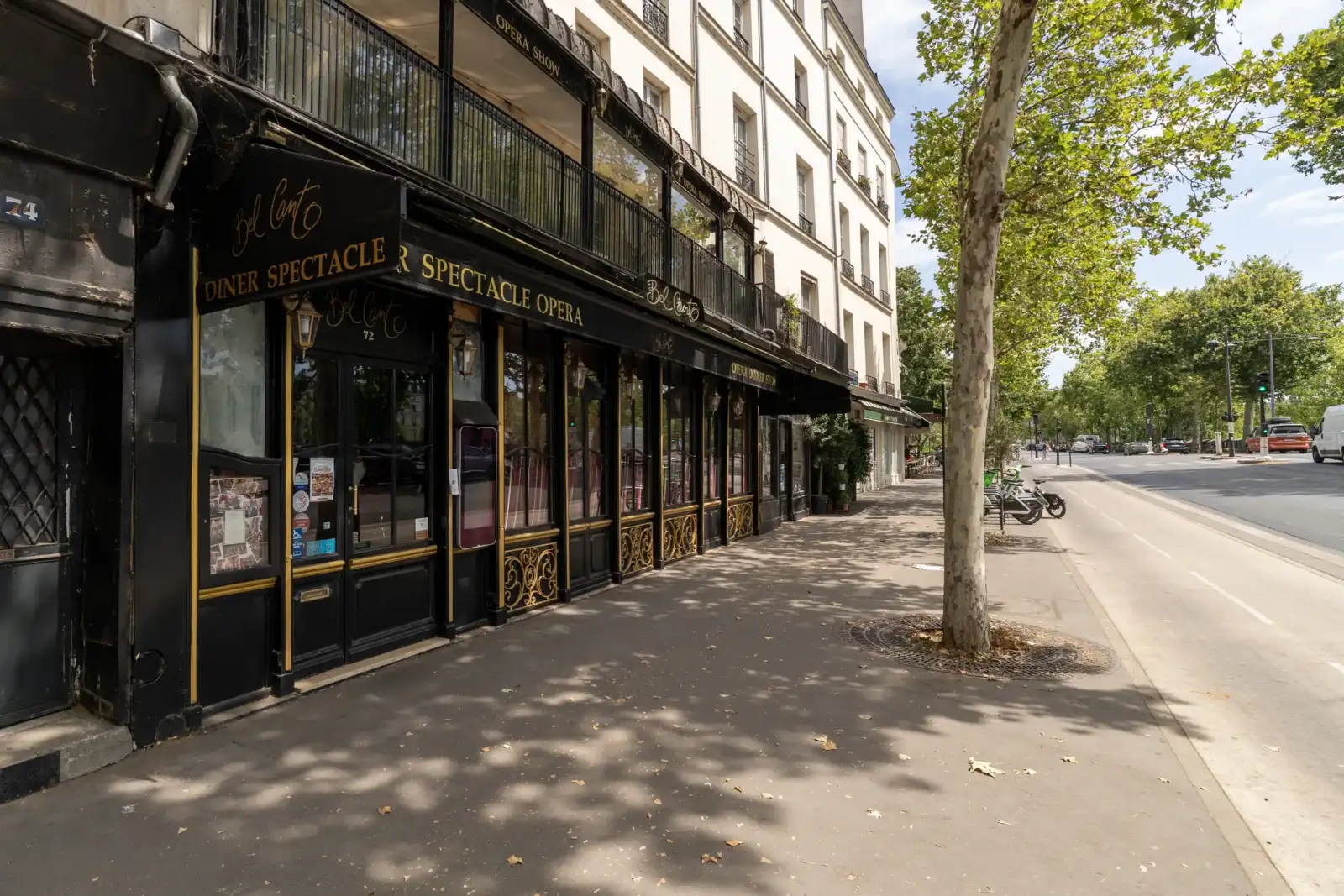 Vue extérieure de la façade noire du restaurant Bel Canto à Paris sur le trottoir ombragé.