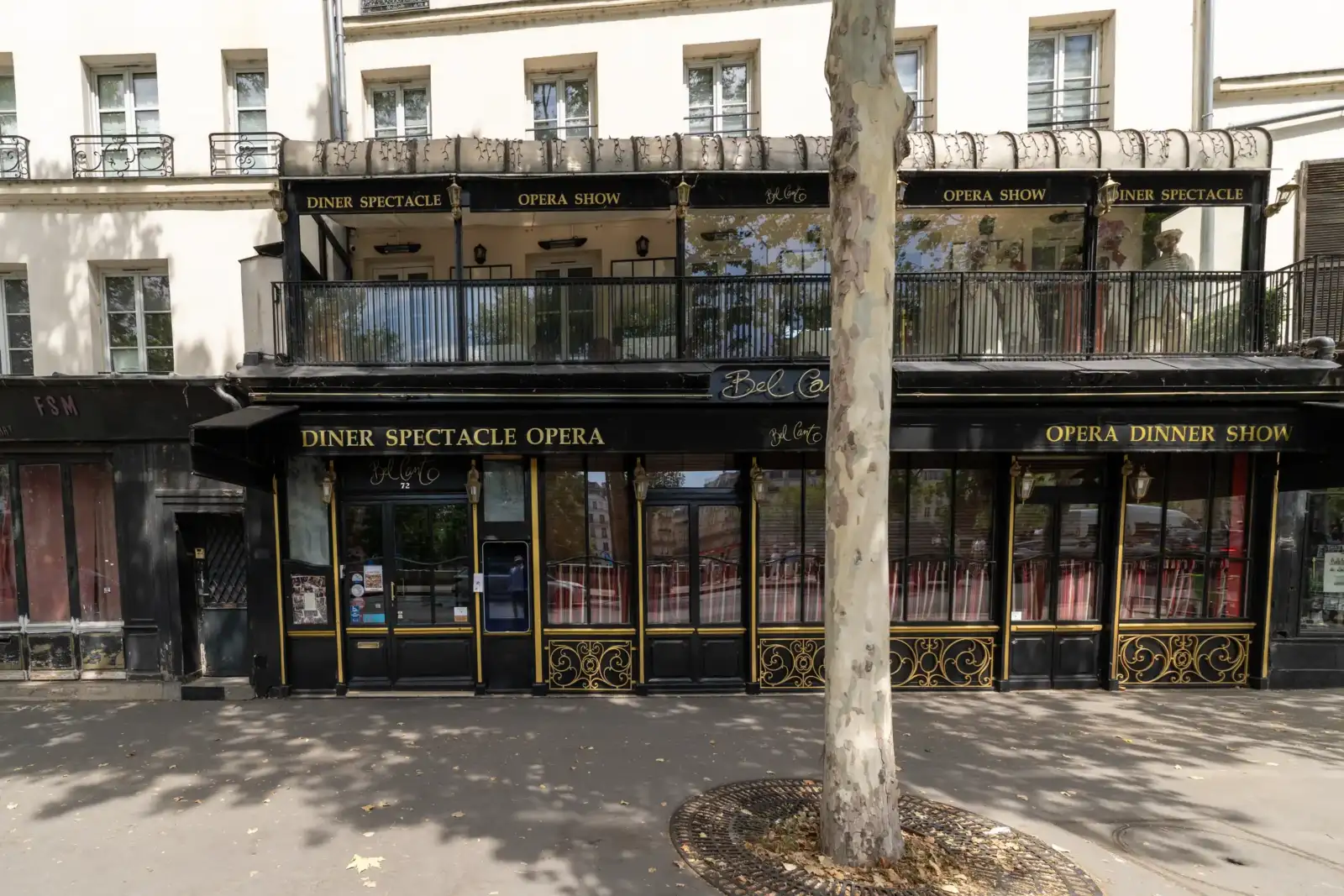 Façade noire et dorée du restaurant Bel Canto à Paris avec un grand arbre.