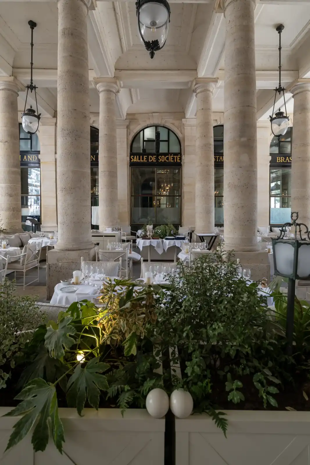 La terrasse couverte du restaurant Le Grand Véfour montre des tables dressées entre des colonnes.