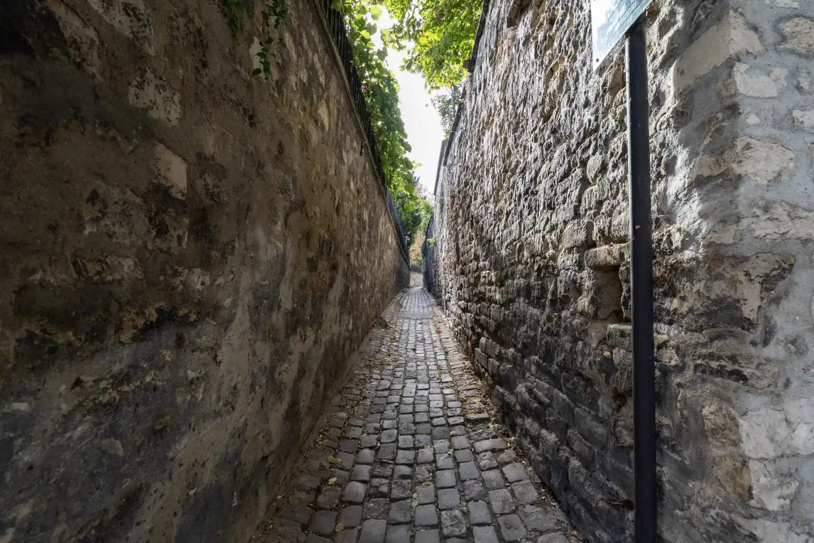 Étroite rue pavée bordée de hauts murs en pierre ancienne à Paris.