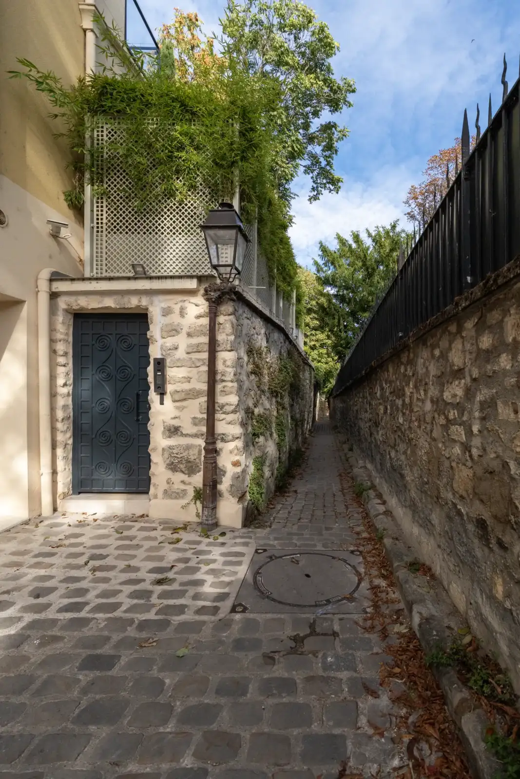 Une ruelle pavée et étroite avec un réverbère et un mur en pierre.