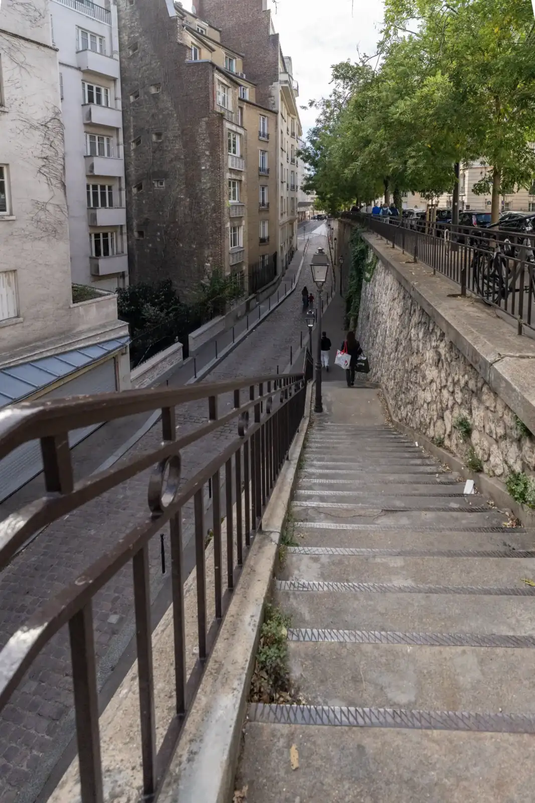 Vue en plongée d un escalier urbain bordé d immeubles parisiens anciens.