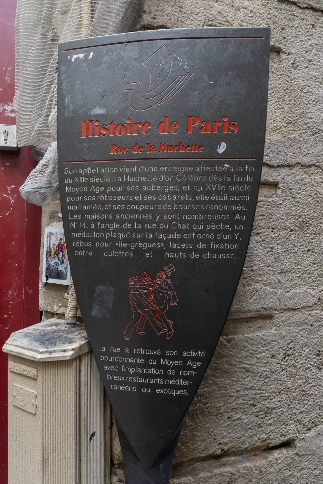 Un panneau noir d'Histoire de Paris fixé sur un mur en pierre ancienne.