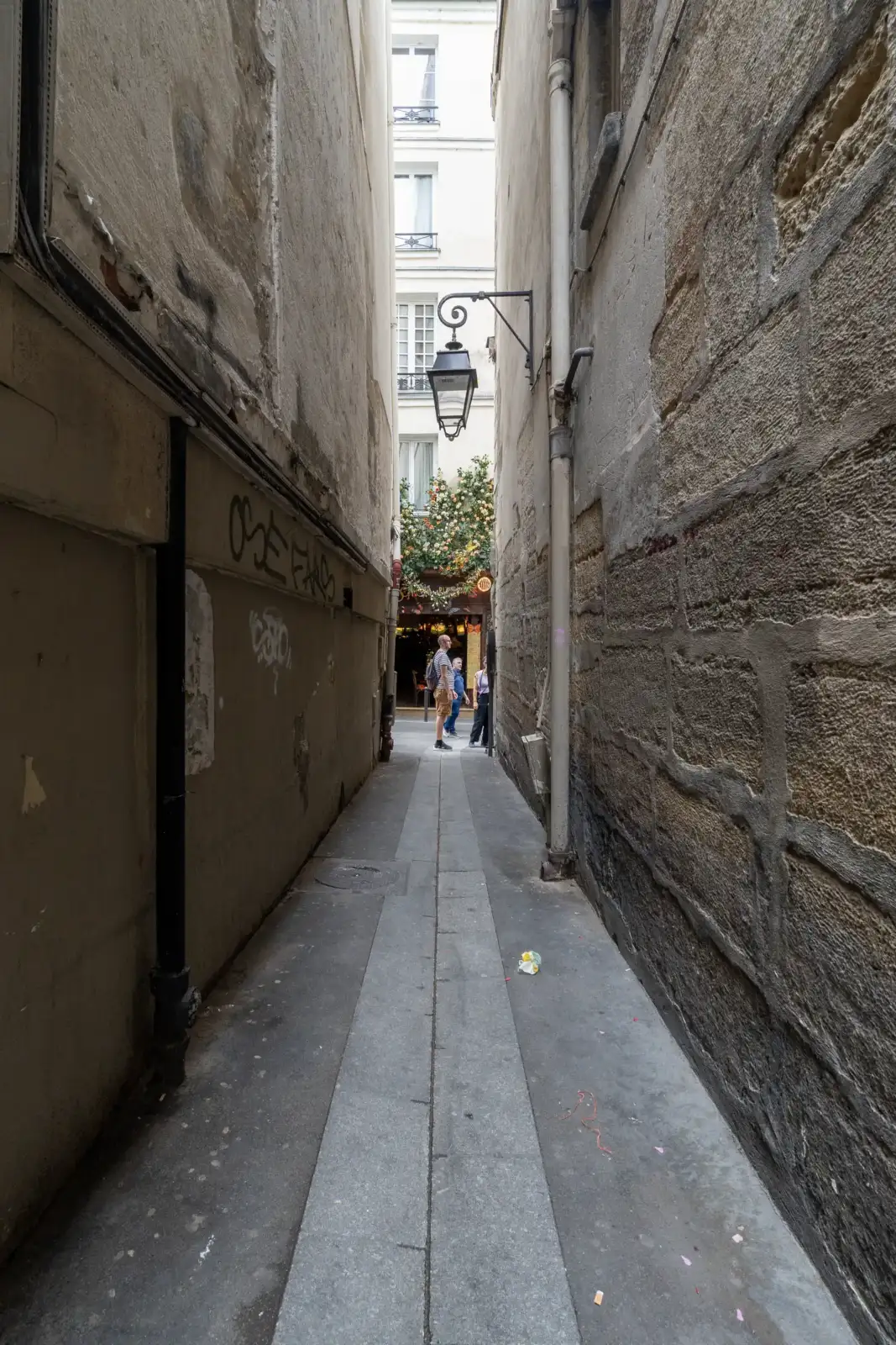 Une ruelle étroite et pavée de Paris encadrée de hauts murs anciens.