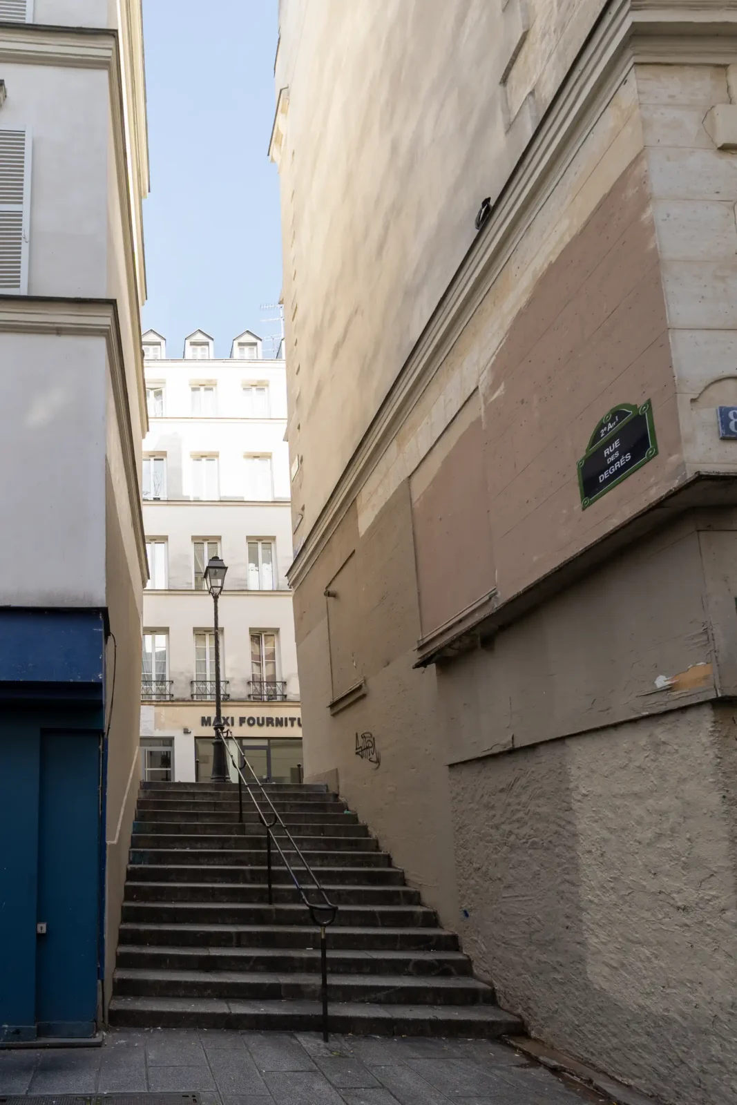 Un escalier en pierre monte entre deux immeubles parisiens vers la rue des Degrés.