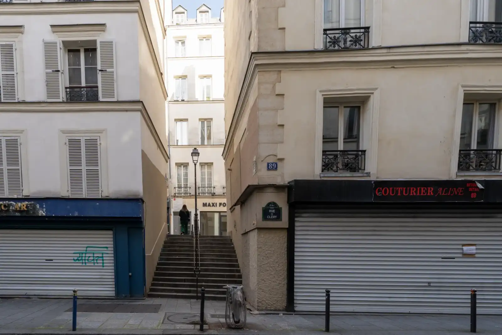 Une personne monte les escaliers de la rue des Degrés entre deux immeubles parisiens.