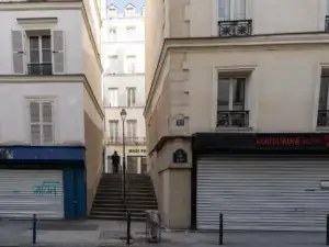 Une personne monte les escaliers de la rue des Degrés entre deux immeubles parisiens.