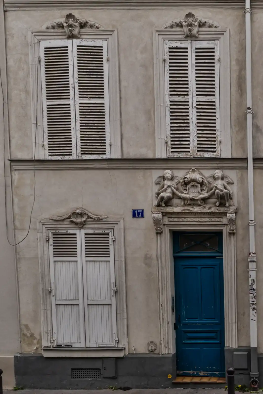 Une façade parisienne ancienne avec une porte bleue et des volets blancs au 17 rue d Eure.