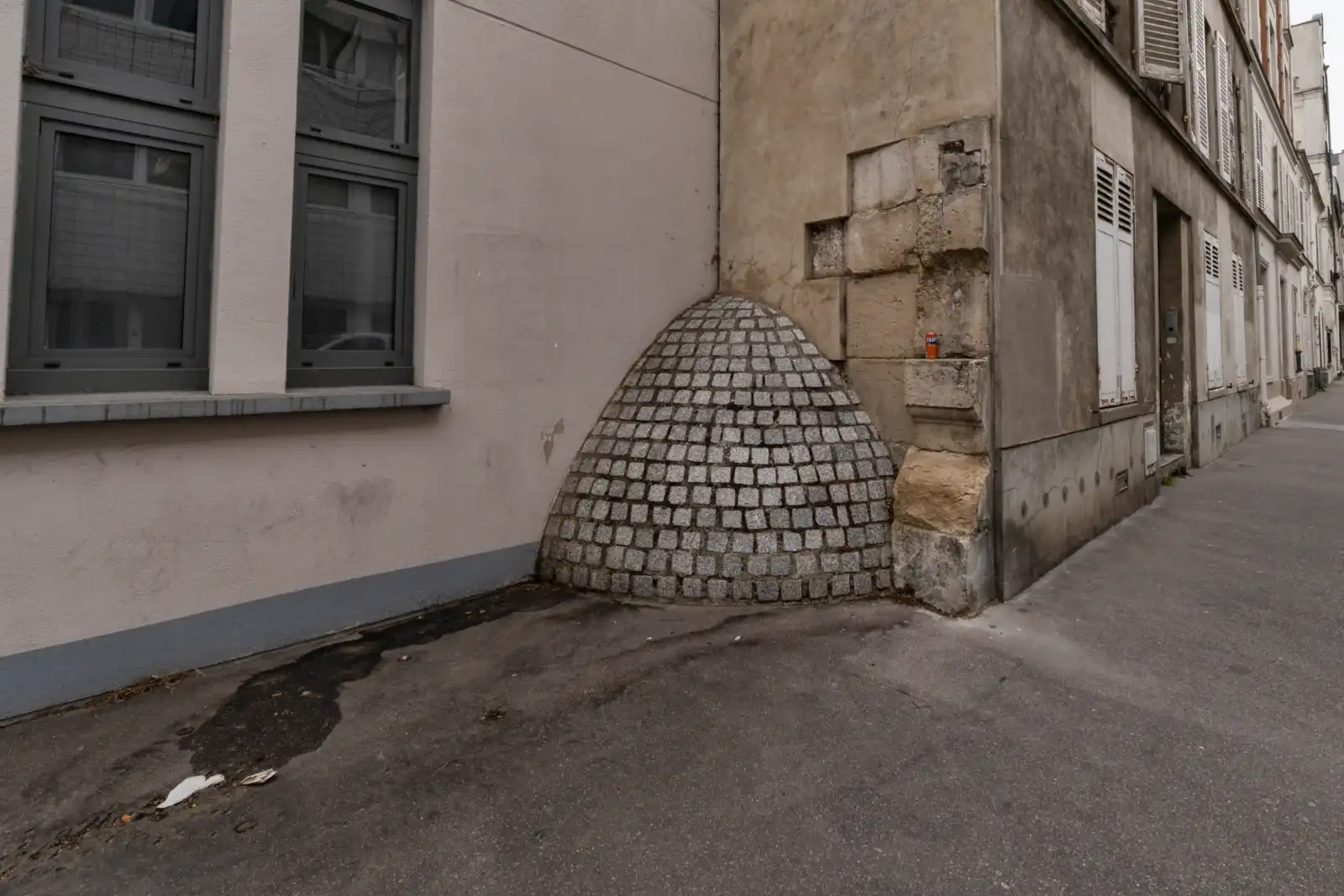 Une demi-coupole en pavés s appuie contre un angle de mur de rue parisienne.