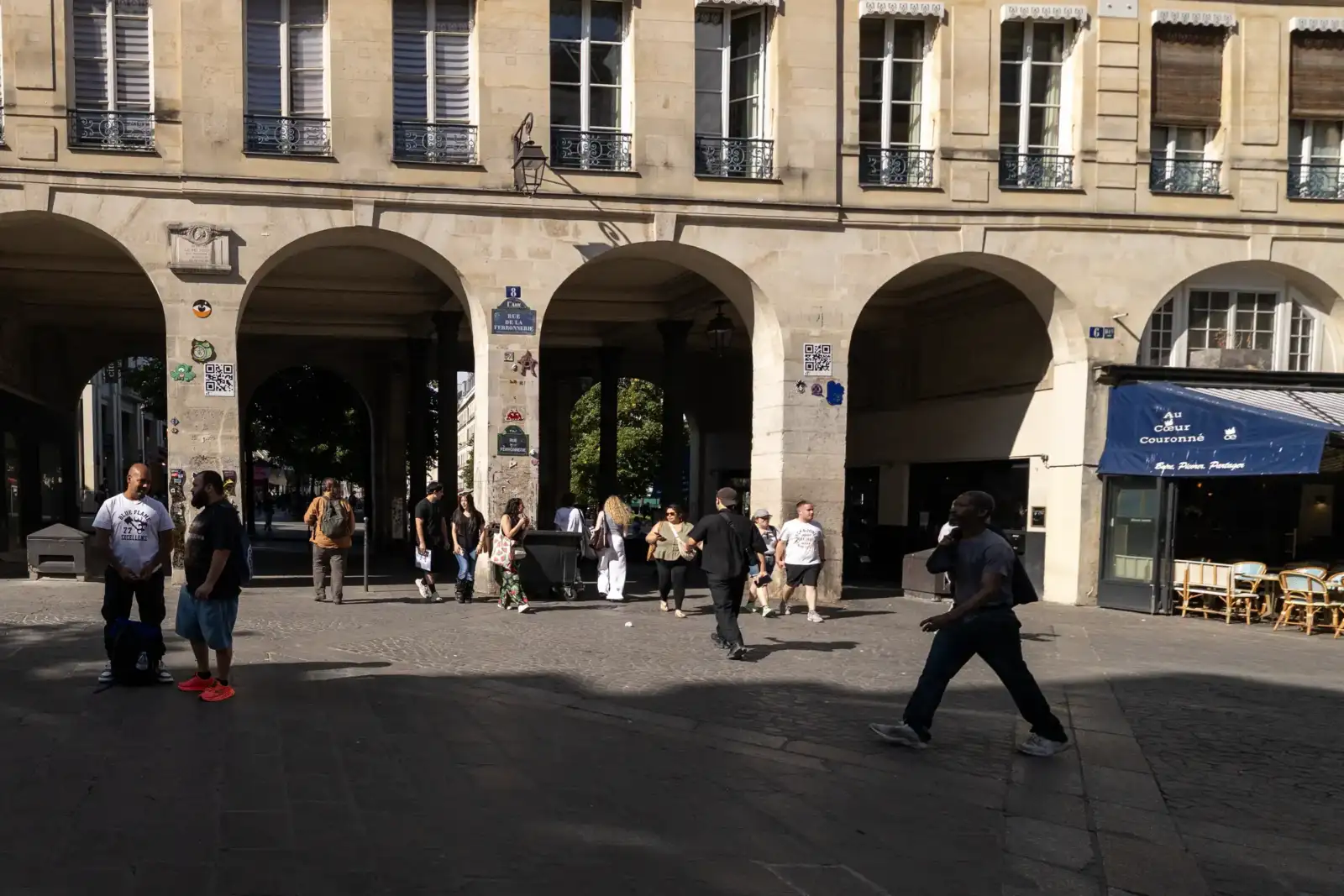 Des piétons marchent sous les arcades historiques de la rue de la Ferronnerie à Paris.