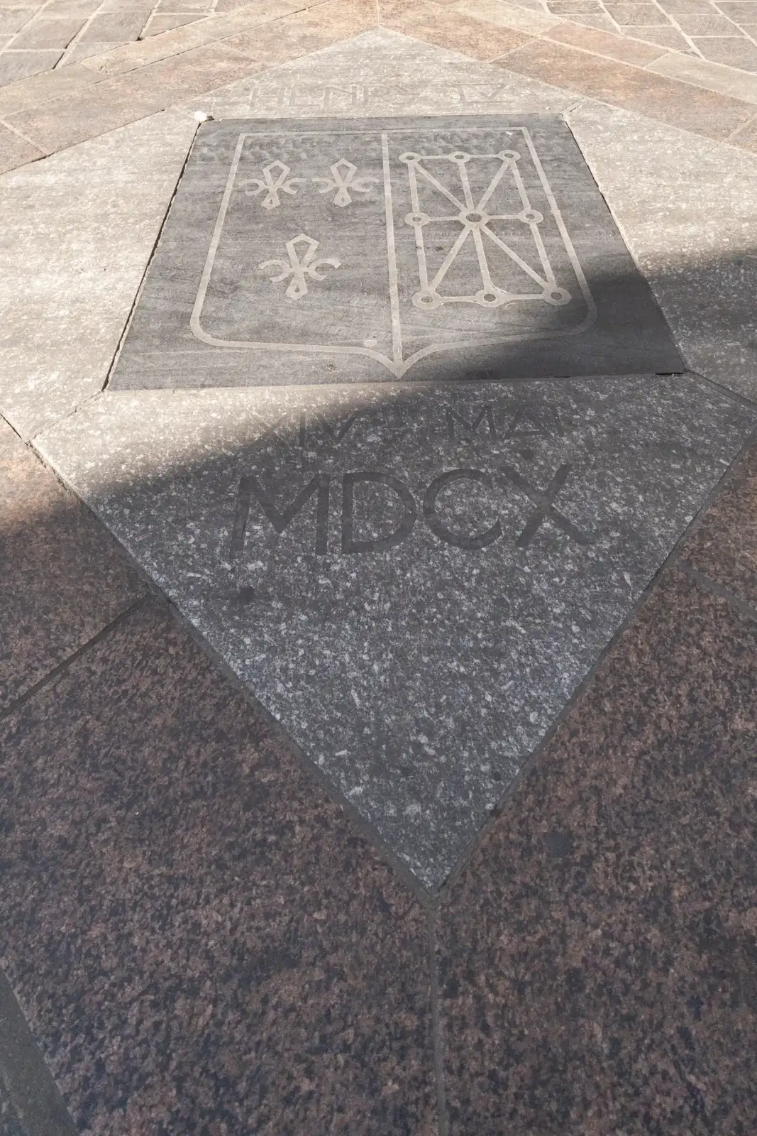 Plaque commémorative en pierre au sol dédiée à Henri IV avec armoiries.