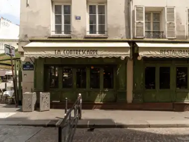 Façade d'un restaurant parisien avec une enseigne bleue indiquant la rue Mouffetard.