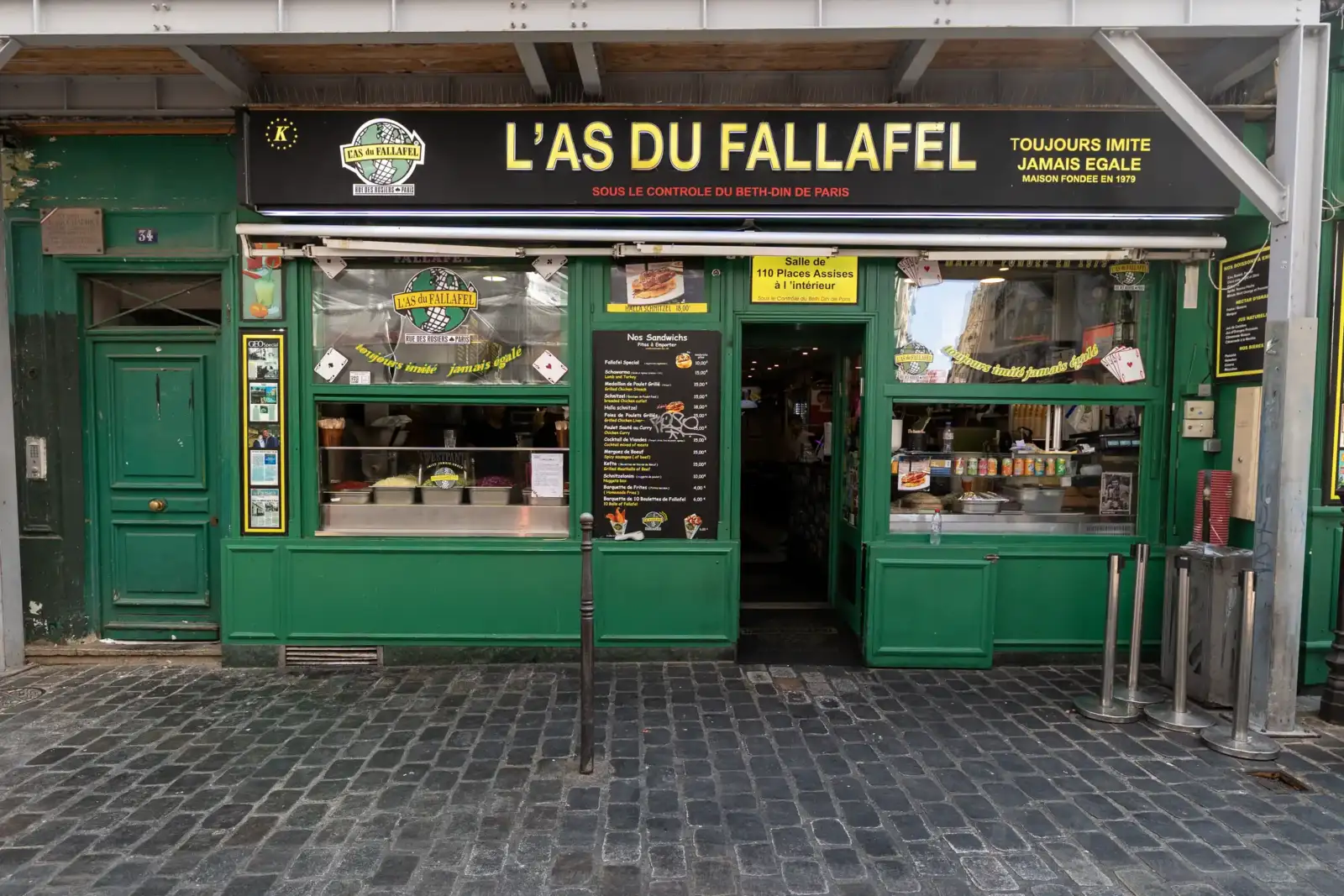 Une façade verte animée du restaurant L'As du Fallafel rue des Rosiers à Paris.