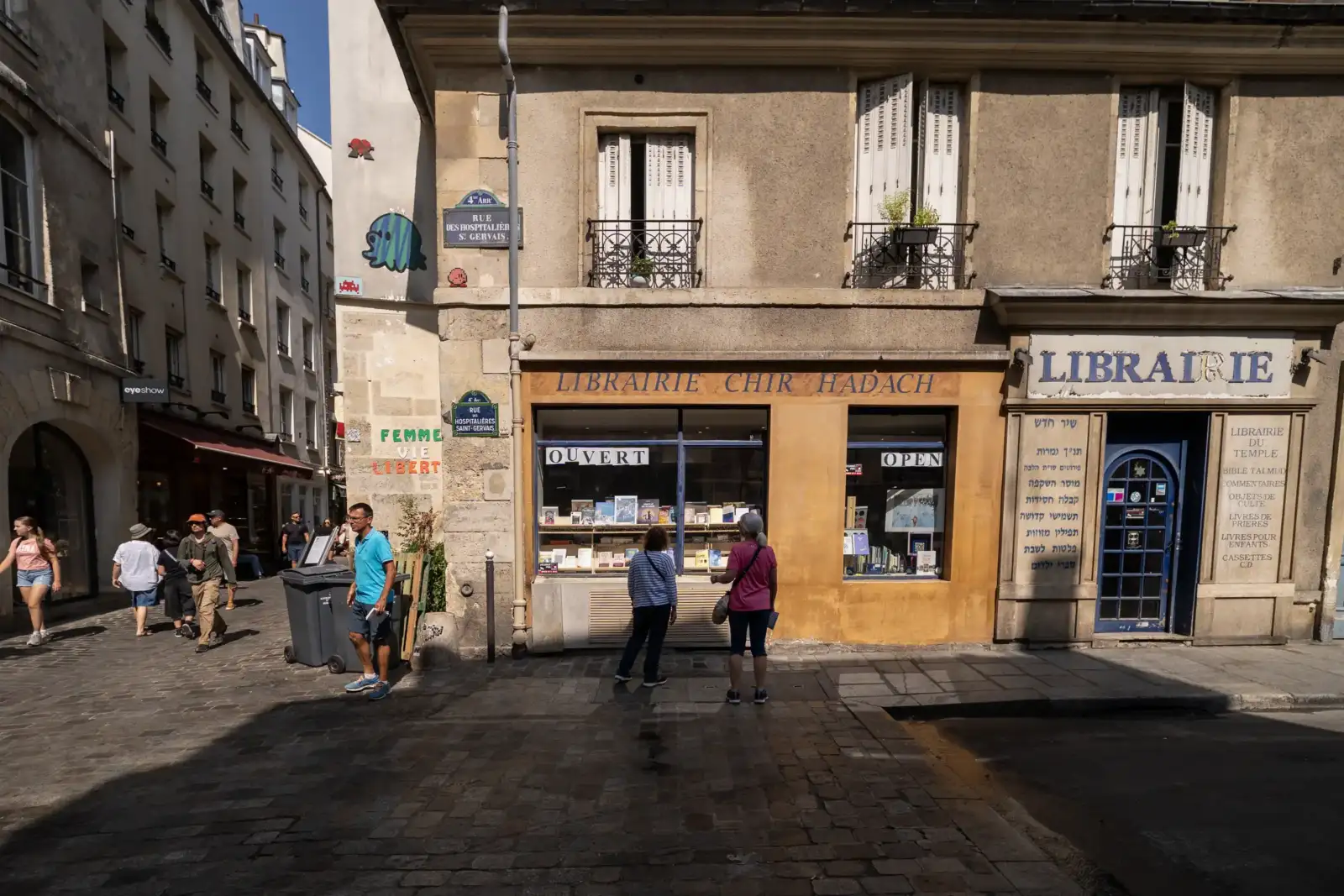 Une rue pavée à Paris avec des panneaux de signalisation et des librairies traditionnelles.